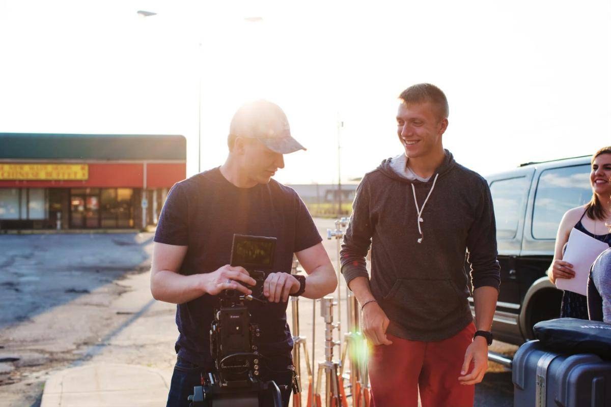 Luke checking a cinema camera with crew on an outdoor shoot at golden hour